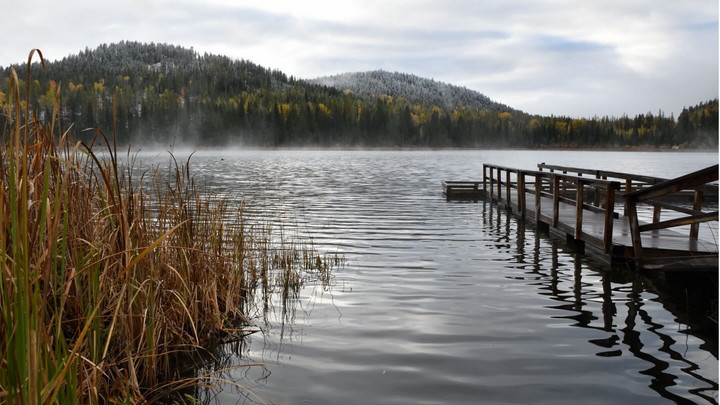 A dock on a lake with forested hills in the background